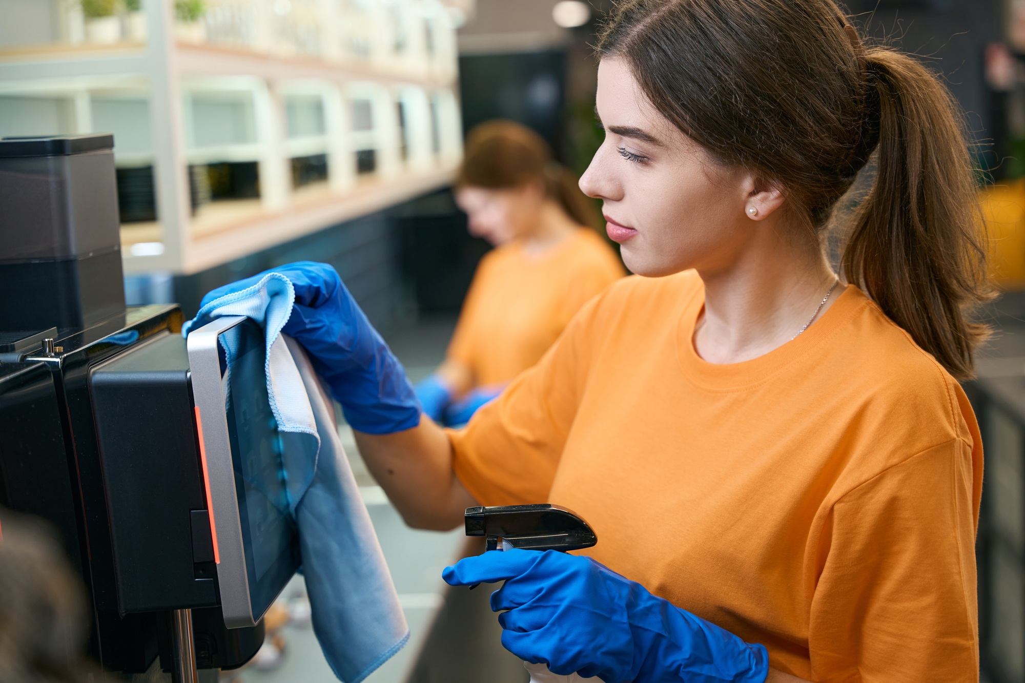 Employee cleaning company washes coffee machine in a coworking area